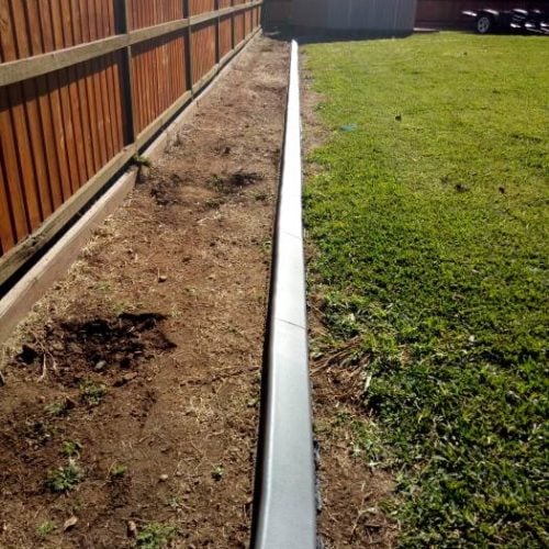 Continuous concrete garden edging kerb parallel to fence
