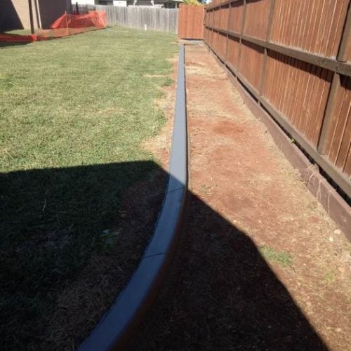 Continuous concrete garden edging kerb parallel to fence
