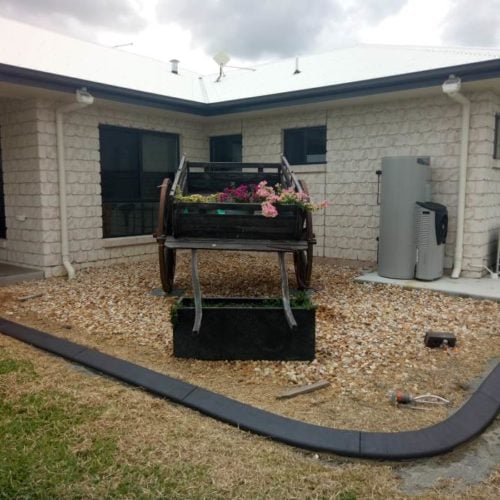 Continuous concrete garden edging kerb around horse cart garden feature